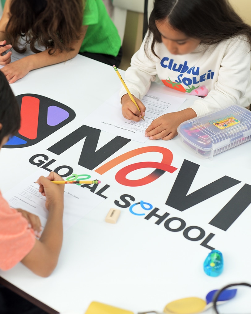 Feed_unlugarparacrear 1 Children drawing at a table with the Navi Global School logo