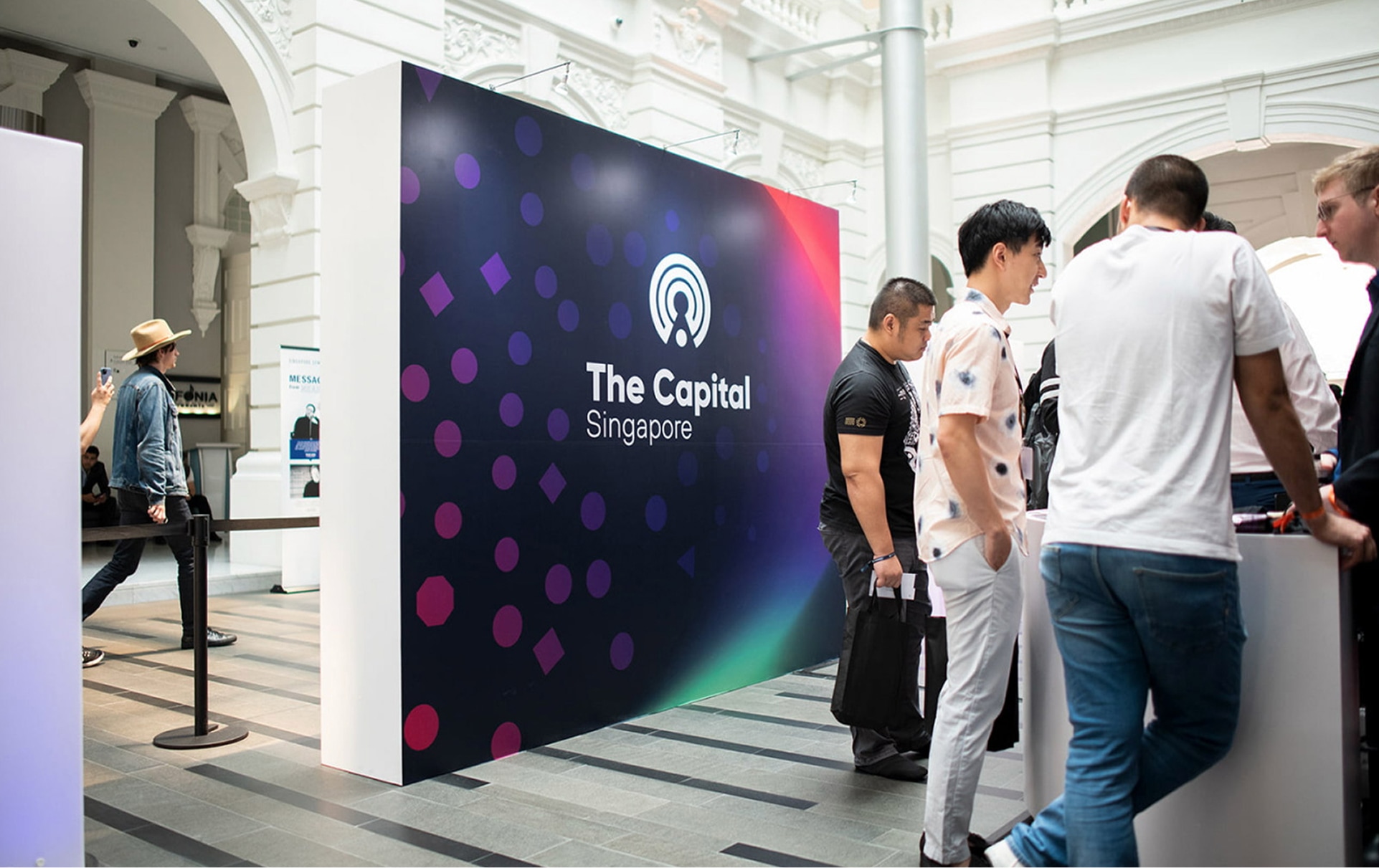Attendees in front of The Capital conference backdrop